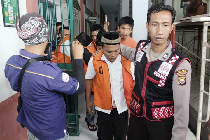 Indonesian police escort Zainal (C-orange) and other suspects as they walk to a court room prior to their trial in Curup, Bengkulu province on September 29, 2016. The leader of an Indonesian gang who murdered and gang-raped a schoolgirl was sentenced to death on September 29, in a high-profile case that led to the introduction of tougher punishments for child sex offenders. / AFP PHOTO / DIVA MARHA