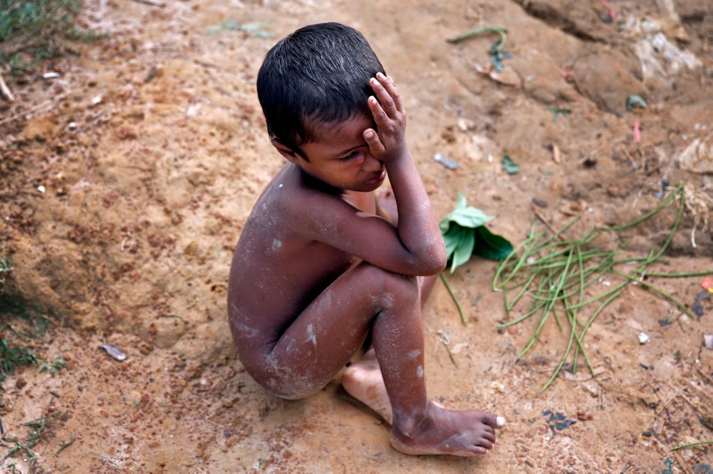 A Rohingya refugee child cries as he sits on the ground in Cox's Bazar